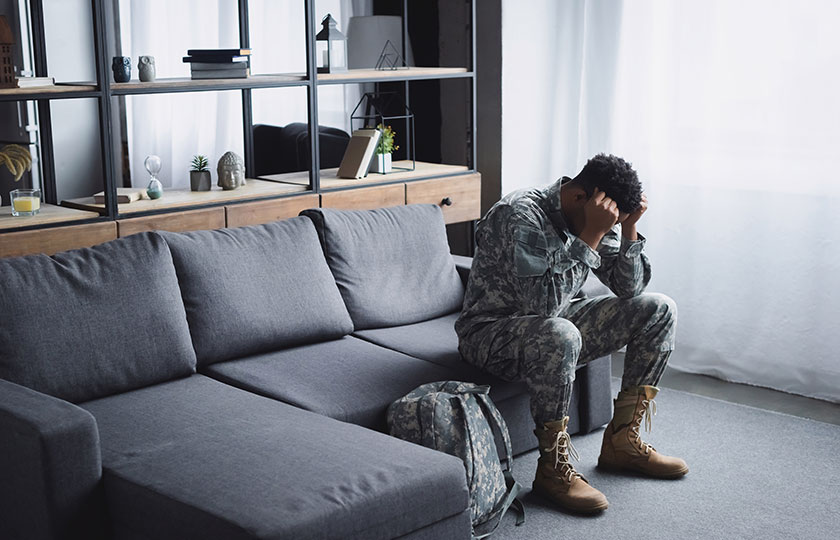 soldier sitting on a couch with his head in his hands