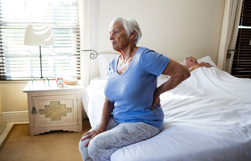 woman with back pain sitting up in bed